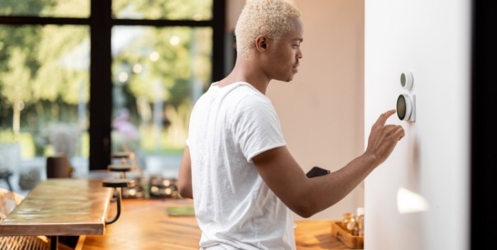 man adjusting thermostat